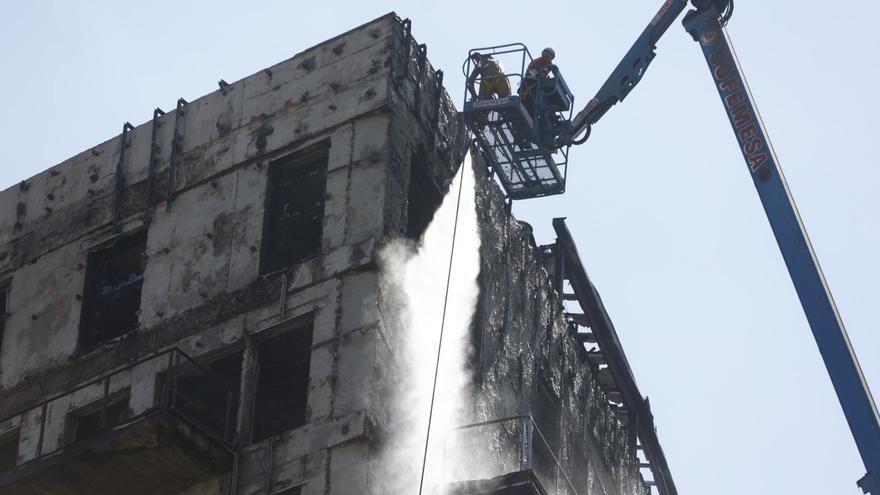 Una grúa limpia con un chorro de agua el edificio incendiado de Campanar